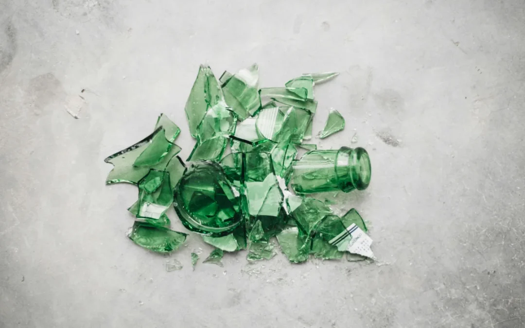 Shards of a broken green bottle on concrete, the state most glass recycling material arrives in