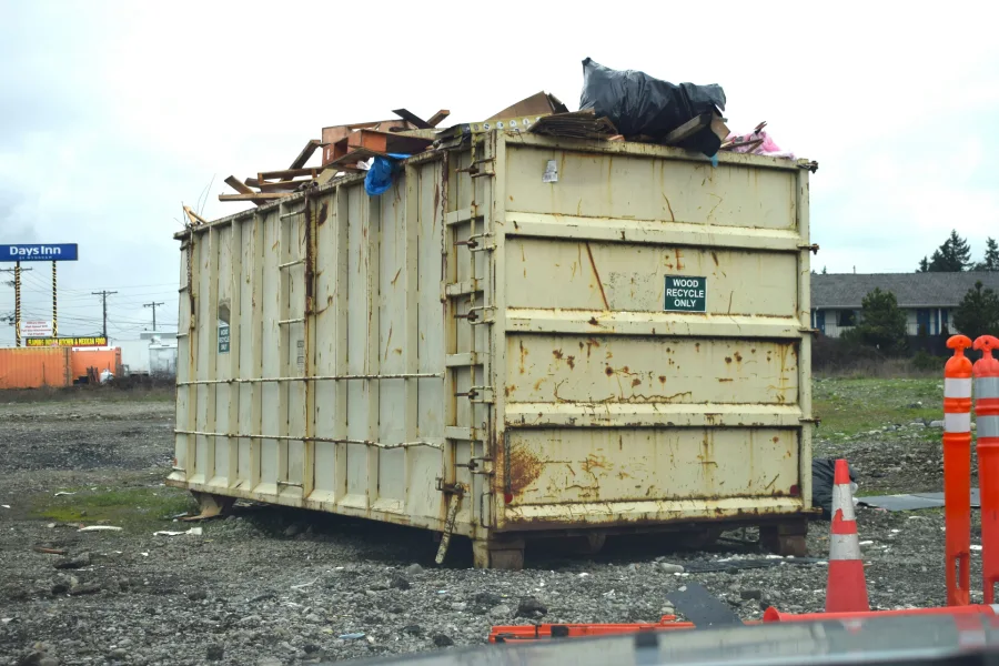 roll-off-container-loaded-wood-recycling-debris Open roll-off container loaded with scrap wood and cardboard, marked for wood recycling only